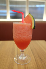 Red drinking straw in a glass of watermelon smoothie.