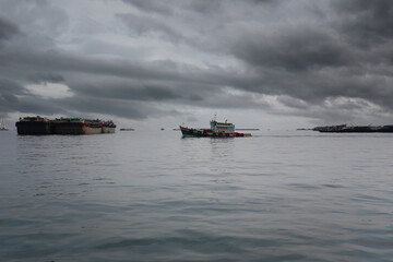 Tug boats and cargo ships moored in the bay of Koh Sichang, Chonburi Province of Thailand.