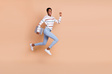 Fototapeta na wymiar Photo of charming sweet unisex person wear sweater running jumping holding device isolated beige color background