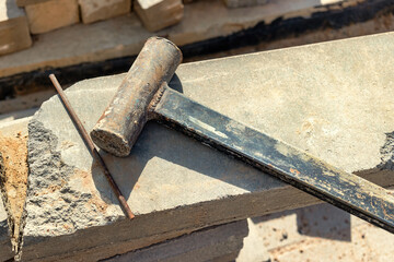 A sledgehammer or hammer made by workers licks on a concrete block at a construction site. Working tool close-up.
