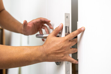 Hand clamped door. A young man shut the door of the house so carelessly and clumsily that the door grabbed his hand finger pinched.