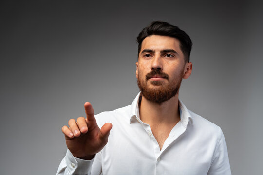 Young Arab businessman working with virtual screen over grey background.