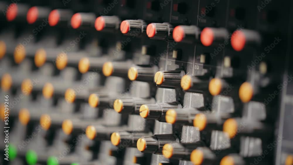 Poster light shining on control knobs of mixing console at recording studio. - close up