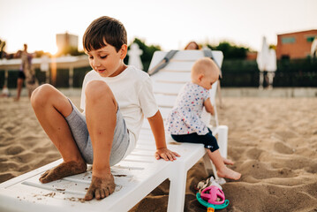 Smiling african american siblings running and wearing swimming suits on sunny beach. healthy, active family beach holiday.