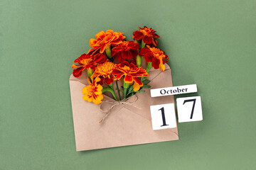 October 17. Bouquet of orange flower in craft envelope and calendar date on green background. Minimal concept Hello fall. Template for your design, greeting card
