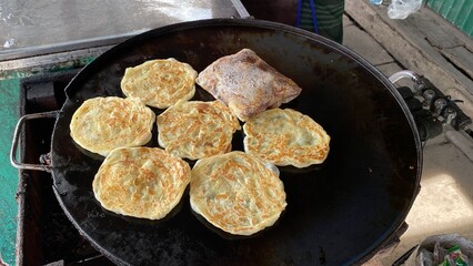 Street hawker preparing prata bread or roti canai for morning breakfast