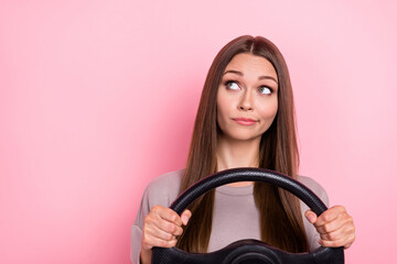 Portrait of minded person hands hold wheel look interested empty space contemplate isolated on pink...