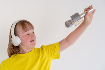 Charming girl 12 years old with down syndrome in headphones sings a song into a microphone. Music...