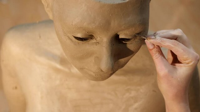 Making A Clay Sculpture - Artist's Hand With Tool Adding Details On The Eye Part Of A Clay Model. - close up