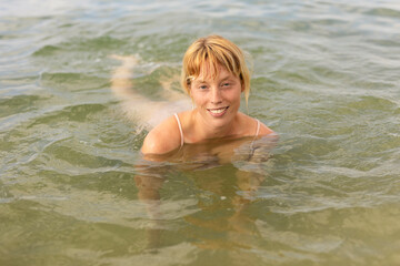 Fototapeta na wymiar Beautiful woman swimming in the ocean. Smiling blonde girl enjoy in sunny day.