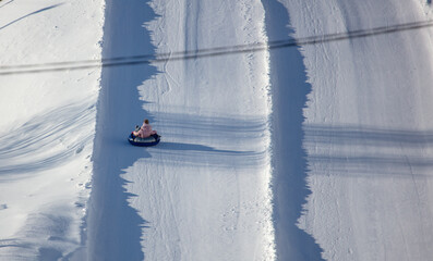 A child rolls down a snow tubing from a mountain.