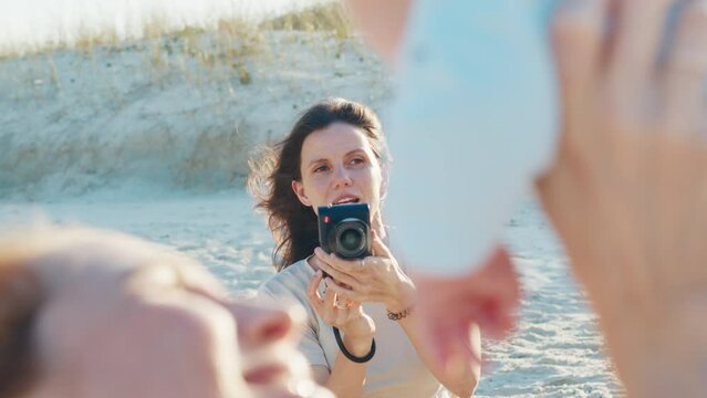 Family photographer. Cheerful woman takes pictures of the woman with kids