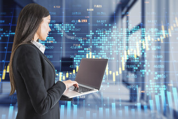businesswoman with laptop and creative forex chart with candlestick graph, index and tech hologram on blurry office interior background. Trade, stock, and finance concept. Double exposure.