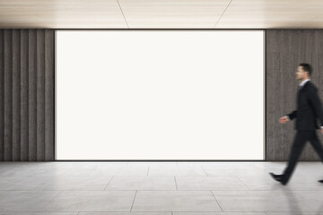 Advertising concept with businessman walking by blank white glowing screen with space for your logo...