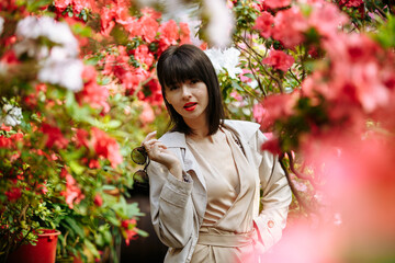 A bright girl in glasses and a short dress among blooming azaleas