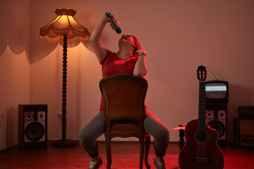 Woman playing music and singing on a wireless microphone in a retro vintage room.
