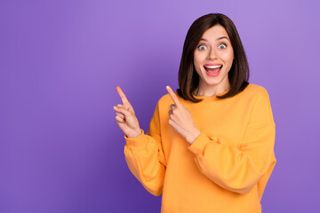 Photo of young funky excited positive lady wear yellow sweater unexpected fingers pointing empty space halloween event isolated on purple color background