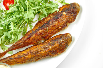 Fried gobies in a white plate. Close-up, selective focus. White background