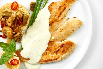 Fried fish fillet with white sauce and couscous. Close-up, selective focus