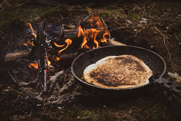 preparing a qurrito over a campfire in the forest