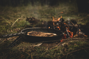 preparing a qurrito over a campfire in the forest