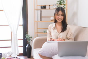 Concept of activity in living room, Asian woman use keyboard to typing data and working on laptop