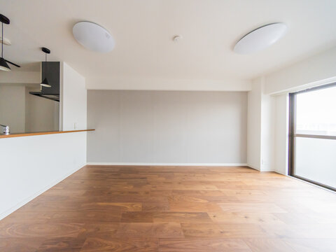 S&eacute;jour vide avec parquet fonc&eacute;, mur gris et comptoir de cuisine