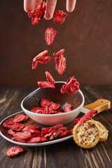 Levitation, Strawberry chips fall into ceramic plate with wooden handle and cookies with chocolate...