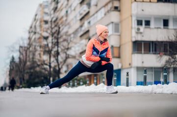Woman does stretching before training in the snow in the winter.