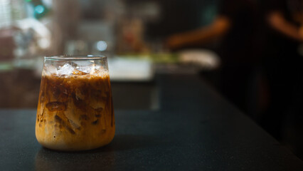 Ice coffee on a table with cream being poured into it showing the texture