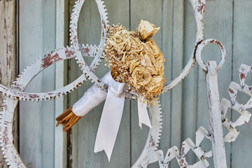 Bouquet of dried roses, tied with white ribbon, in door made of metal gears