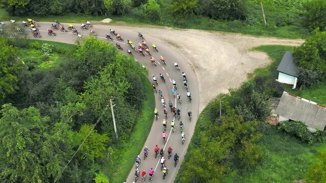 Aerial view A peloton of cyclists enters a sharp turn in the countryside. Overcoming the marathon distance on a bicycle by a group of cyclists.