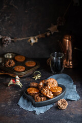 Homemade delicious chocolate mini cakes on the wooden plate on the table with coffee and christmas decoration. Dark and moody