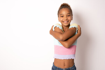 I love myself. Portrait of pleased satisfied mixed race girl hugging herself and smiling isolated...