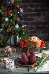Delicious and tasty sweet pears boiled in red wine and a glass of wine on the christmas decorated table. 