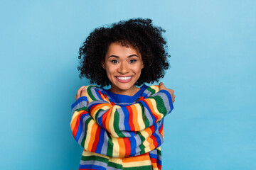 Photo of young curly hairdo lady hug herself wear colorful sweater isolated on blue color background