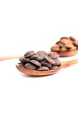 Close up of delicious dark and milk chocolate drops in wooden spoon isolated on white background. Vertical photo