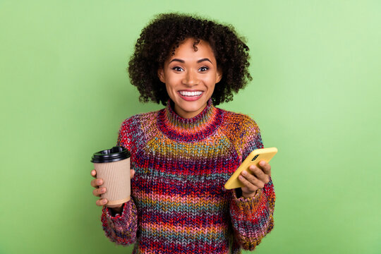 Photo of funky young valume hairdo lady hold telephone cup wear colorful turtleneck isolated on green color background