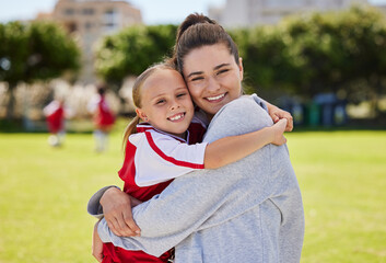 Portrait of mother and girl hug at soccer training, bonding and embracing on a field. Sport,...