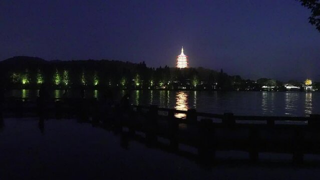 illuminated old tower by west lake at twilight in hangzhou
