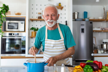 Happy senior man having fun cooking at home - Elderly person preparing health lunch in modern kitchen - Retired lifestyle time and food nutrition concept