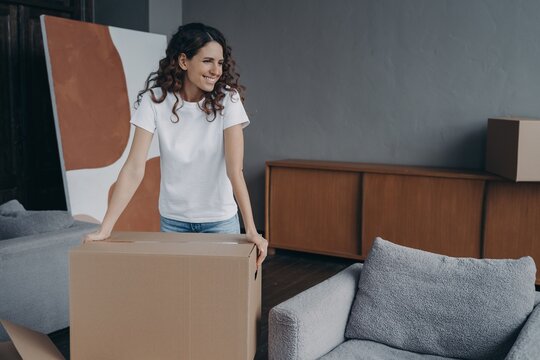 Smiling woman with box preparing for house renovation or relocation, dreaming about modern new home