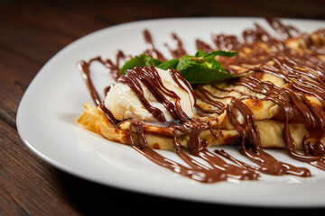 Pancake with a scoop of ice cream and chocolate. Close-up, selective focus
