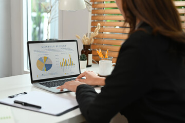 Asian businesswoman working with laptop computer and financial document at her workplace