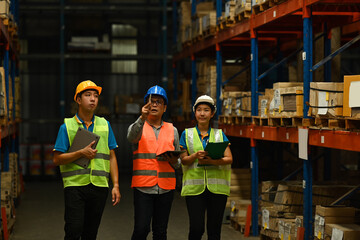 Warehouse workers wearing safety hardhat working on retail warehouse full of packed boxes and goods