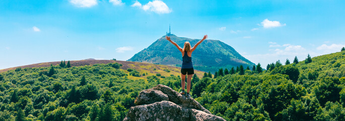 Hiker woman looking at panoramic view of mountain ( Puy de dome,  Auvergne in France)
