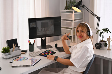 Young creative woman using graphic tablet and professional computer working for design project at...