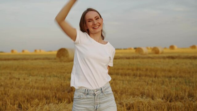 Gorgeous woman in a wheat field against the sunset. Fashionable girl with long hair rejoices, laughs. 