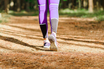 Fototapeta na wymiar Female runner jogging outdoors through a summer forest trail.Close up.Copy space.