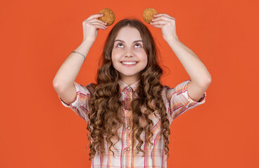 Fototapeta premium glad teen child with oatmeal cookies on orange background